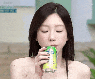 a woman drinking from a can of sprite with her eyes closed