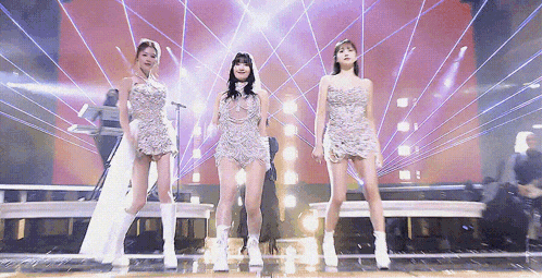 a group of three women are standing on a stage in front of a microphone .