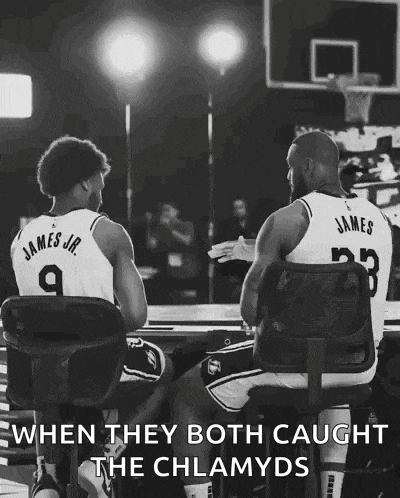 two basketball players are sitting in chairs talking to each other .