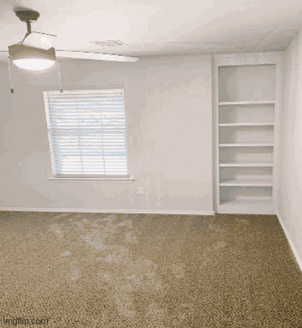 an empty room with a ceiling fan and shelves