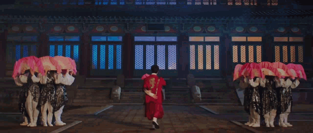 a group of people in traditional korean clothing are holding pink fans