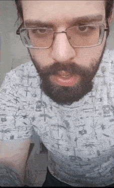 a man with glasses and a beard is wearing a t-shirt with skulls on it