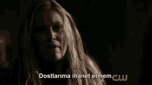 a woman in a dark room with the words `` dostlarima ihanet etmem '' written on the bottom of her face .