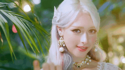 a woman with white hair and a butterfly in her hair is wearing a white dress and earrings .