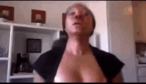 a woman 's breasts are visible in a video while she looks at the camera .