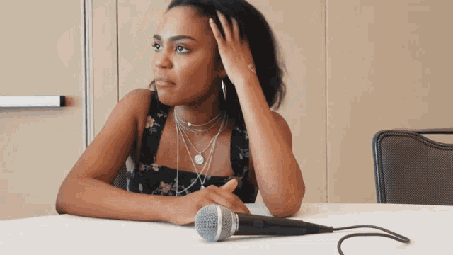 a woman is sitting at a table with a microphone in front of her