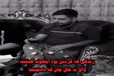 a man sits on a couch with a cup of coffee in his hand and a caption in a foreign language