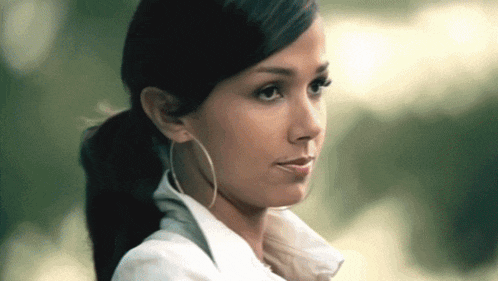 a woman wearing hoop earrings and a white shirt looks to the side
