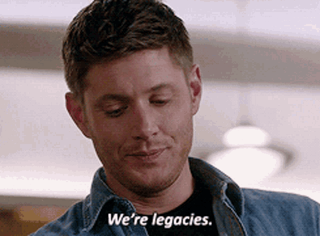 a man in a denim shirt is smiling and saying we 're legacies .