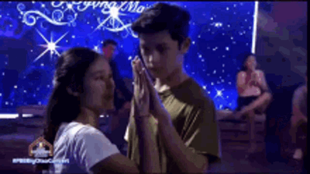 a boy and a girl are dancing in front of a screen that says ' pretty ' on it