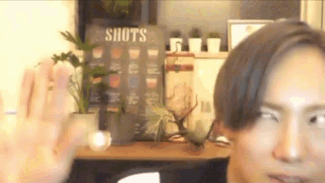 a man is sitting in front of a sign that says shots on it .