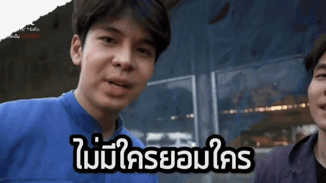 a man in a blue shirt is talking to another man in a purple shirt in a video .