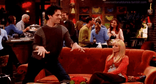 a man is dancing with a woman sitting on a red couch