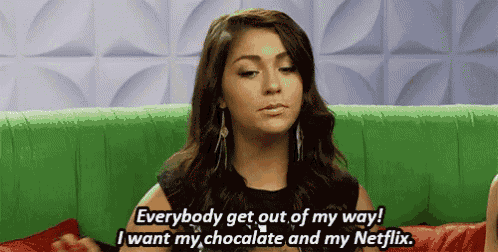 a woman sitting on a green couch says everybody get out of my way i want my chocolate and my netflix .