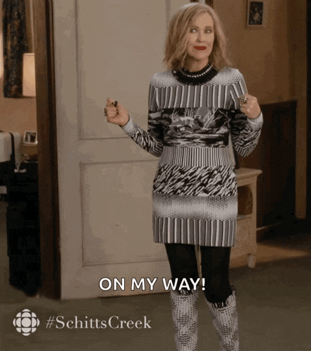 a woman in a sweater and boots says on my way in front of a door