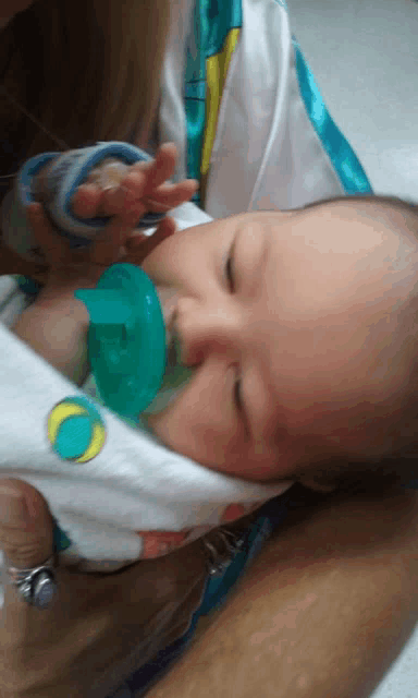 a baby with a pacifier in his mouth is being held by a person