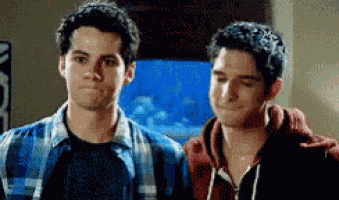 two young men are standing next to each other in front of an aquarium and looking at each other .