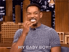 a man is laughing and saying `` my baby boy '' while holding something in his mouth .
