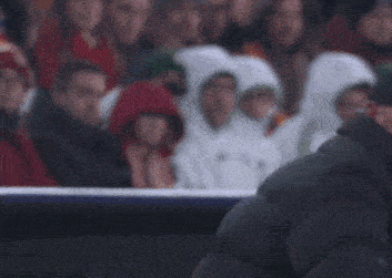 a man in a black jacket is dancing on a soccer field in front of a cooler that says bank