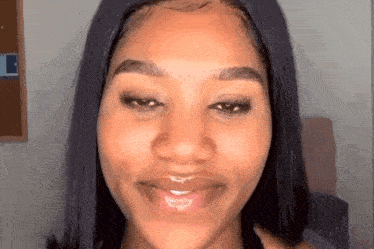 a close up of a woman 's face with long black hair and a smile on her face .