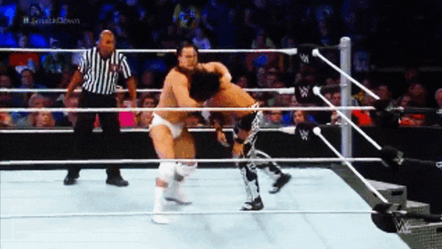 two wrestlers in a wrestling ring with a referee and the words # smashdown on the screen