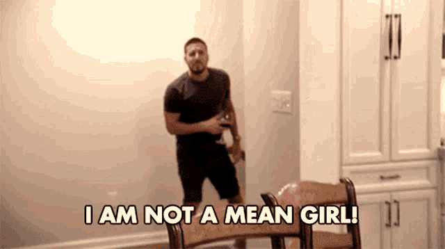 a man is standing next to a chair and saying i am not a mean girl !