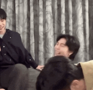 a group of people are sitting on a couch laughing and talking to each other .