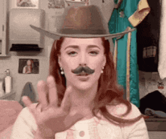 a woman wearing a cowboy hat and fake mustache waving