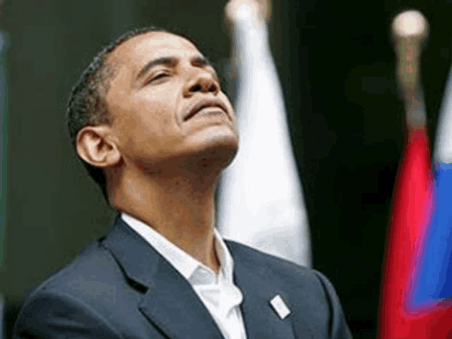 barack obama is looking up at the sky while standing in front of a row of flags .