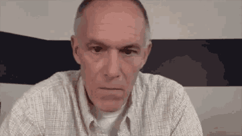a man in a plaid shirt is sitting in front of a blue and white striped wall .