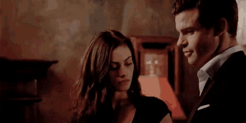 a man and a woman are looking at each other in a dark room .