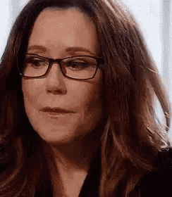 a woman wearing glasses and a black shirt is making a funny face .
