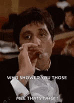 a man in a tuxedo is smoking a cigar and talking to someone .