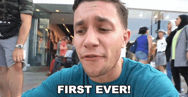 a man in a blue shirt says first ever in front of a crowd of people