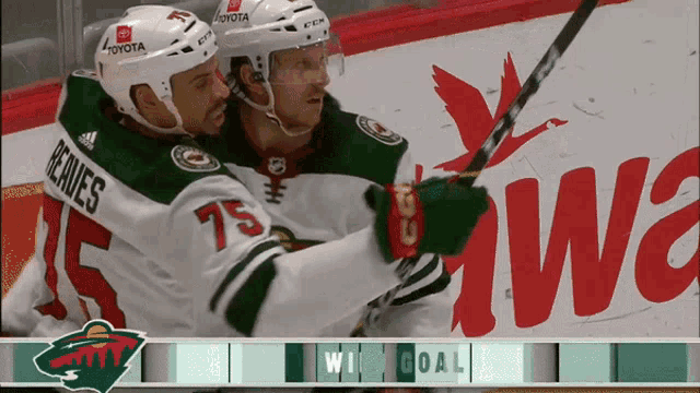 two hockey players are celebrating a win with toyota in the background