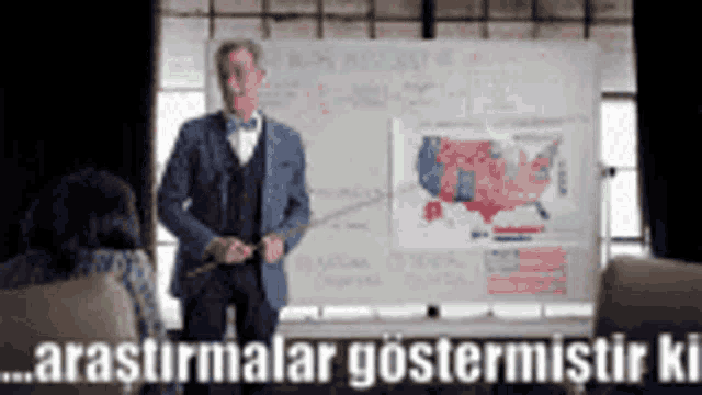 a man in a suit stands in front of a white board with a map of the united states