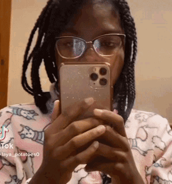 a woman wearing glasses is holding a cell phone in front of her face