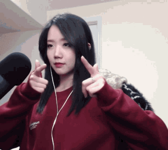 a girl wearing a red sweatshirt that says ' supreme ' on it giving a peace sign