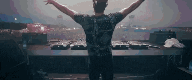 a dj with his arms outstretched standing in front of a crowd
