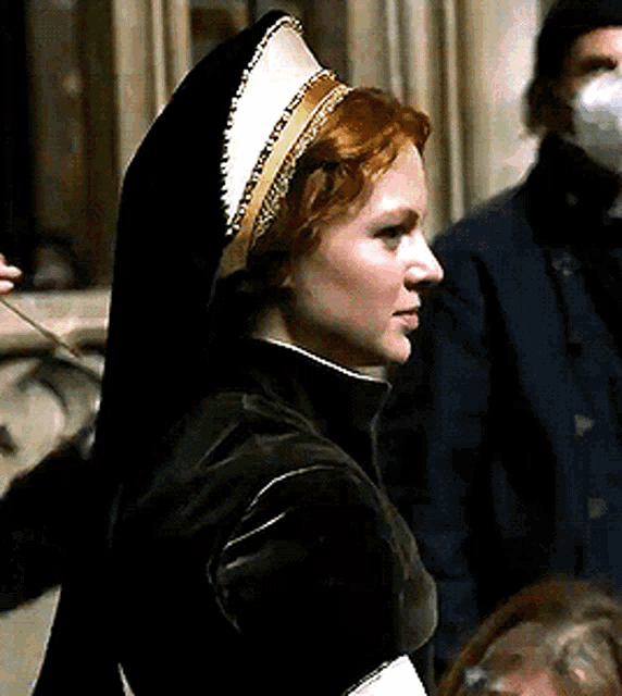 a woman with red hair is wearing a black hooded jacket