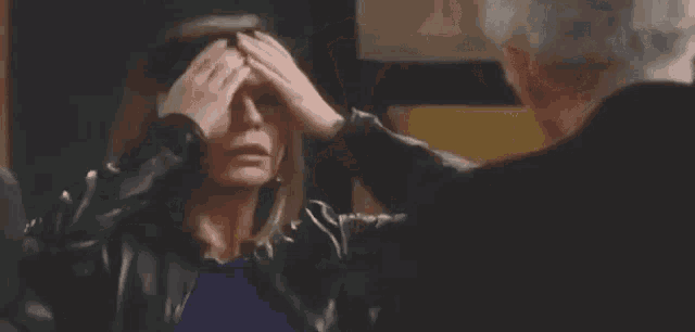 a man is touching a woman 's forehead in a close up .