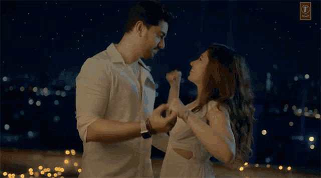 a man and woman are dancing in front of a sign that says ' t ' on it
