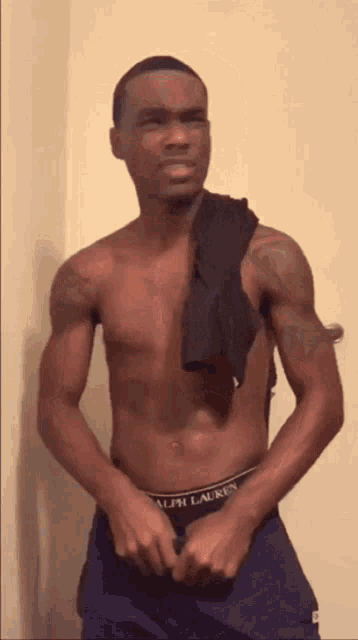 a shirtless man in ralph lauren underwear is standing in front of a wall