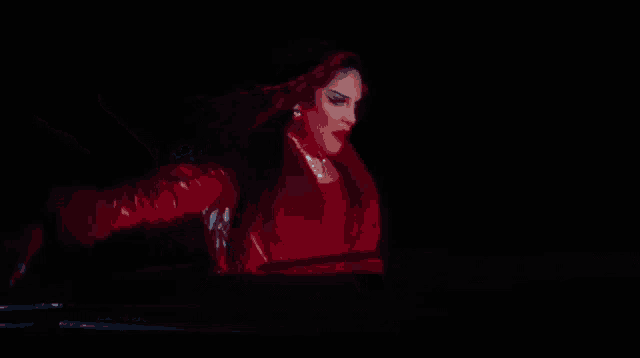 a close up of a woman in a red outfit with her arms outstretched