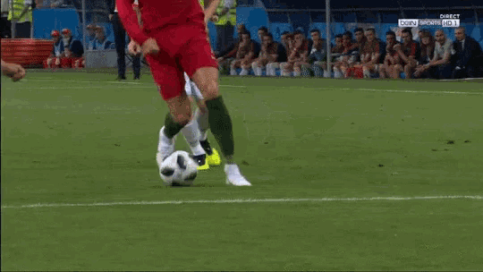 a soccer player is kicking a soccer ball while another player tries to block him