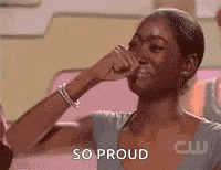 a woman is covering her nose with her hand while another woman holds her hand to her face and says `` so proud '' .