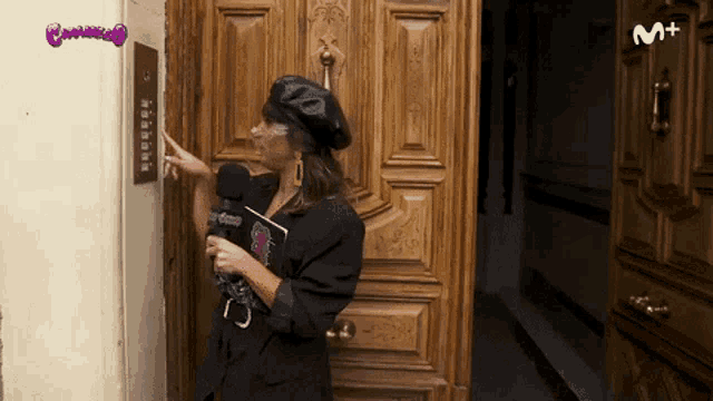 a woman stands in front of a door with a m + logo on the bottom