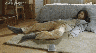 a woman is laying on the floor next to a cell phone