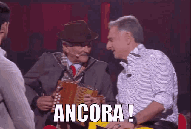 a man in a hat is holding an accordion and the word ancora is next to him