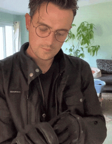 a man wearing glasses and a black jacket with the word shimano on it